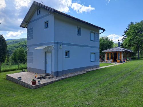 a blue house on a yard with a house at Ris kuca za odmor in Foča