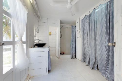 a white bathroom with a sink and a shower at The French Lady Guest House - Entire House in Caye Caulker