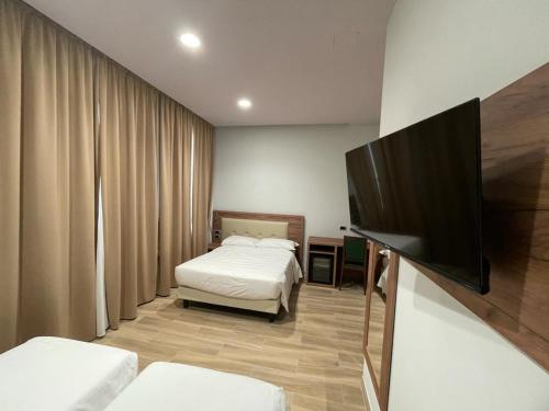 a bedroom with two beds and a flat screen tv at Hotel Central Station in Milan