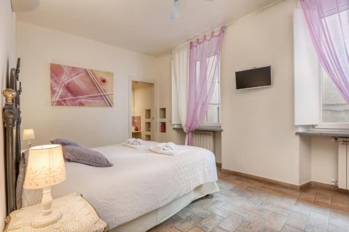 a white bedroom with a bed and a lamp at Viterbo Antica - centro storico in Viterbo