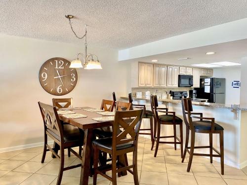 a dining room with a table and chairs and a clock at Wind Drift 102S by ALBVR - 2BR, 2BA Beautiful Upgraded Beachfront Condo near Flora Bama, Outdoor Pools and Tennis Courts in Orange Beach