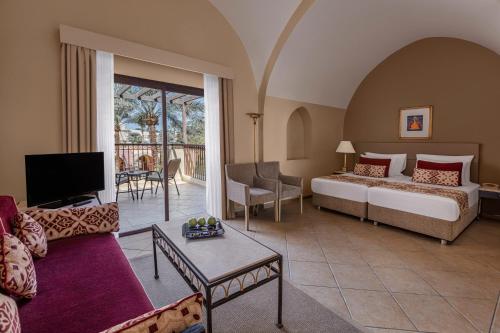 a hotel room with a bed and a living room at Jaz Makadi Saraya Resort in Hurghada