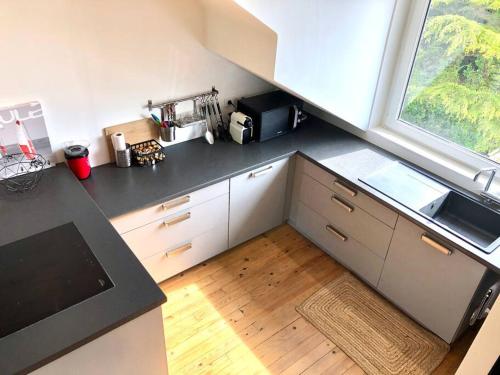 une cuisine avec un comptoir noir et une fenêtre dans l'établissement Chez LouChris, à La Baule