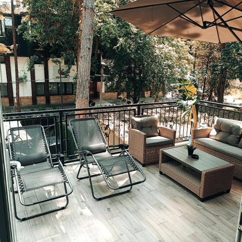 a patio with chairs and a couch and an umbrella at RB Apartment 1 (SPA) & 2 in Palić