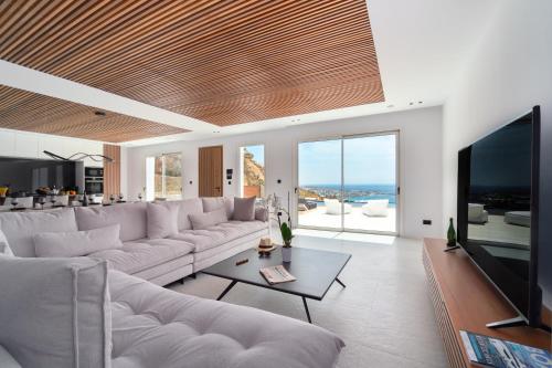 a living room with a large couch and a television at Elit Villa Psarou in Psarou