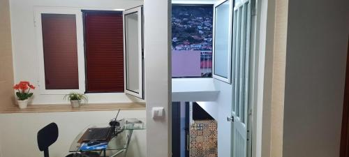a room with two windows and a desk with a laptop at Casa da Avó in Machico