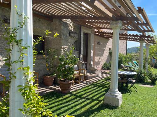 a patio with a wooden pergola and a table and chairs at Chiesa Ignano 1778 in Marzabotto