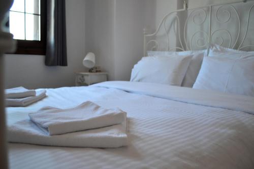 a white bed with white sheets and towels on it at Aegean View House in Agios Ioannis Pelio