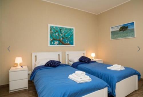 two beds in a bedroom with blue sheets and towels at VIOLET HOUSE. in Catania