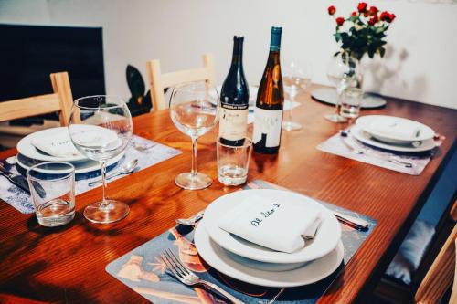 a wooden table with plates and wine glasses on it at Experience in Valle Varaita - Rustico con SPA Privata - Piscina - Sauna - Hammam - Free Wi-Fi in Brossasco