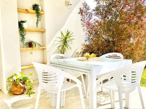 einen weißen Tisch und vier weiße Stühle auf einer Terrasse in der Unterkunft היחידה ליד הנחל עם הנוף לחרמון 33 in Sde Nehemia