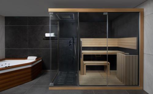 a bathroom with a shower with a bench and a tub at Medi Terre Boutique Hotel - By Saida Hotels in Netanya