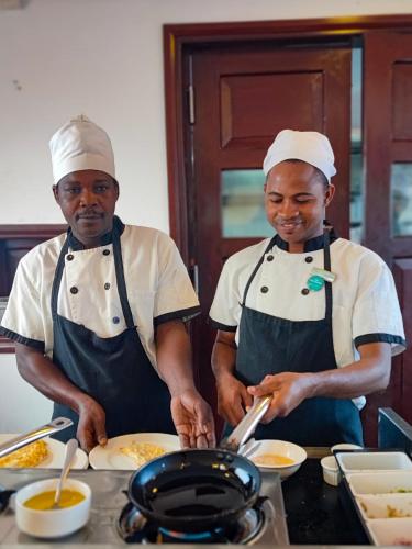 two chefs standing in a kitchen preparing food at Maru Maru Hotel in Zanzibar City