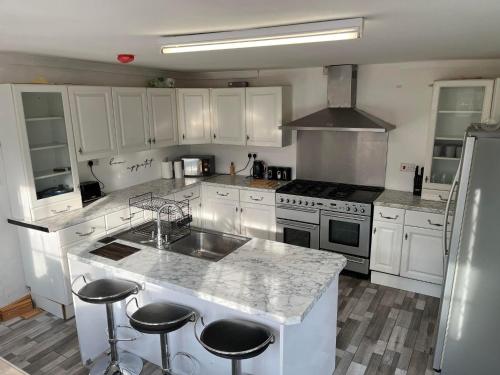 a kitchen with white cabinets and a island with bar stools at Willow House in Birmingham