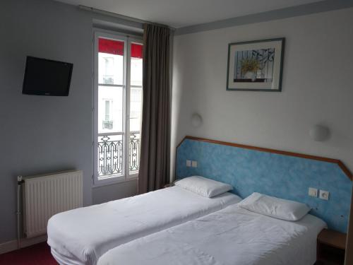 ein Hotelzimmer mit 2 Betten und einem Fenster in der Unterkunft Hotel Royal Mansart in Paris