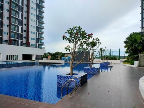 une piscine avec des chaises bleues et un arbre à côté d'un bâtiment dans l'établissement MyHome S1 At Seri Kembangan With A View, à Seri Kembangan