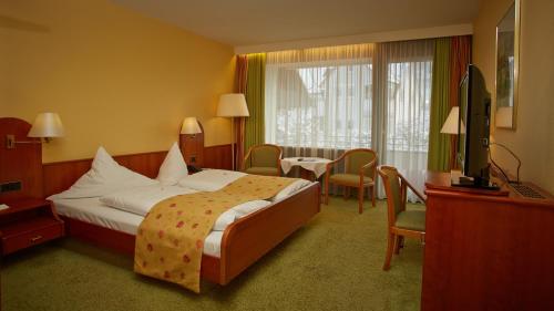 カルフにあるホテル クロスター ヒルサウのベッド、デスク、テレビが備わるホテルルームです。