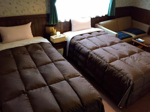 una habitación de hotel con 2 camas y una silla en Morinouta en Nikko