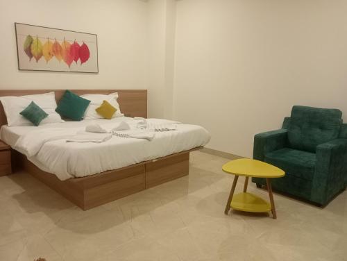 a bedroom with a bed and a green chair at Hotel New Centro in Gulbarga