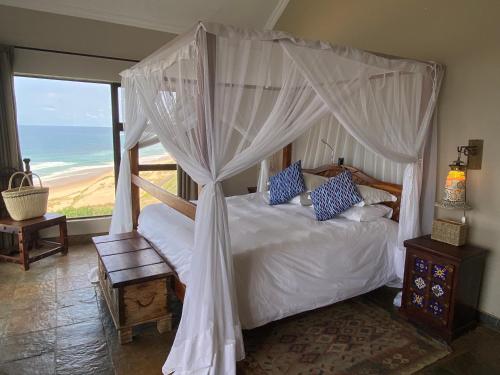 a bedroom with a canopy bed with a view of the ocean at Villa Castellos in Inhambane