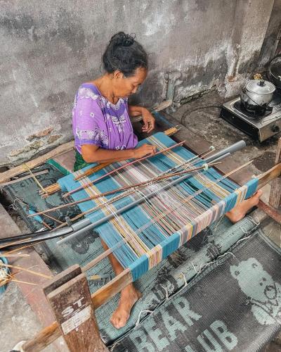 a woman is working on a table with wooden sticks at Jonny's Places in Tetebatu