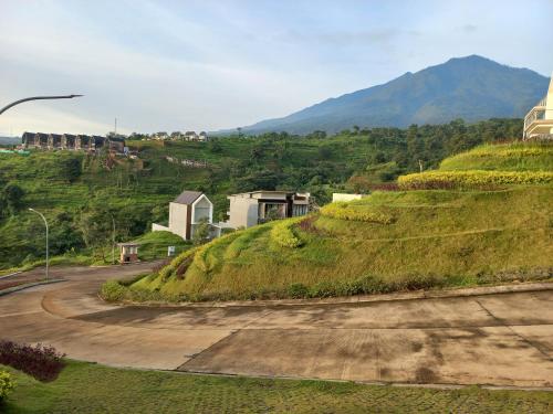 a dirt road with a grassy hill with a house at Villa Canyata in Pasuruan