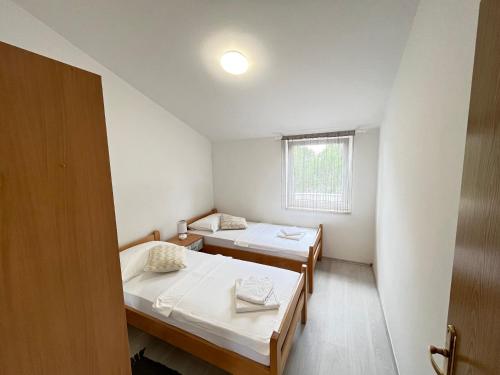 Habitación pequeña con 2 camas y ventana en Vir Apartman Alena en Vir