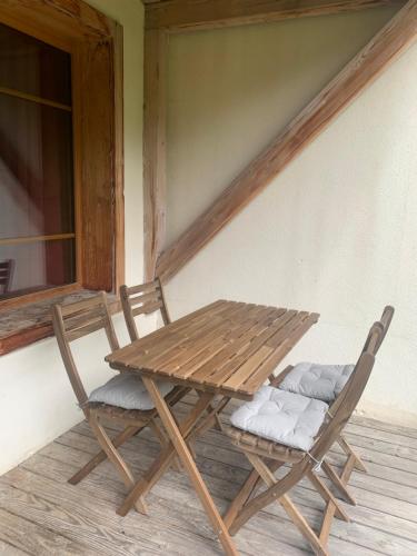 - une table de pique-nique en bois et 2 chaises sur une terrasse couverte dans l'établissement Appartement Les Chalets de Belledonne, à Saint-Colomban-des-Villards