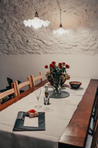 a table with red roses in a vase on it at Experience in Valle Varaita - Rustico con SPA Privata - Piscina - Sauna - Hammam - Free Wi-Fi in Brossasco