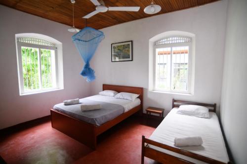two beds in a room with two windows at Irene's Home in Matale
