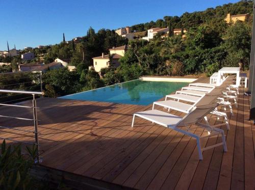 - un groupe de chaises assises sur une terrasse à côté d'une piscine dans l'établissement Magnifique villa vue mer dans le golfe de St-Tropez, à Roquebrune-sur Argens