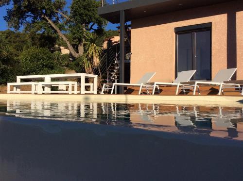uma piscina com duas cadeiras e uma casa em Magnifique villa vue mer dans le golfe de St-Tropez em Roquebrune-sur-Argens
