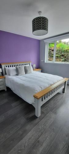 a bedroom with a large bed with a bench on it at River side in Dingle