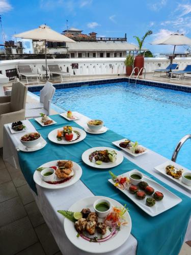 a table with plates of food next to a swimming pool at Maru Maru Hotel in Zanzibar City
