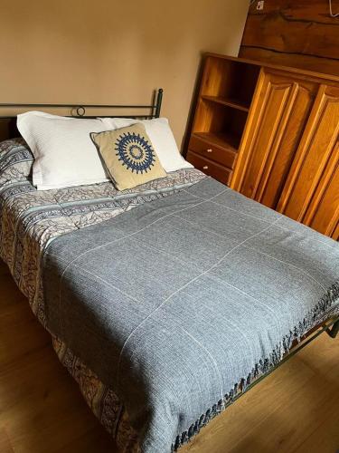 a bed with a blue blanket and a pillow on it at Cabañas El Viejo Sauce in Tandil