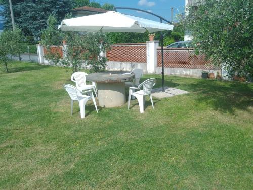 una mesa, sillas y una sombrilla en un patio en Casa Camilla en Capannori