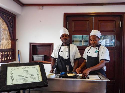 two chefs standing in a kitchen preparing food at Maru Maru Hotel in Zanzibar City