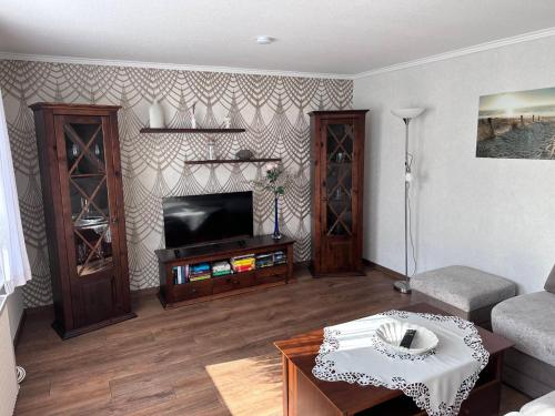 a living room with a flat screen tv and a table at Ferienhaus/Bungalow Lobbe - 60qm in Lobbe