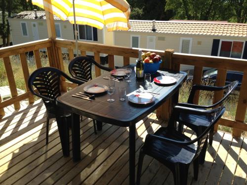 a table and chairs on a deck with an umbrella at Easyatent Mobile home Zelena Laguna in Poreč