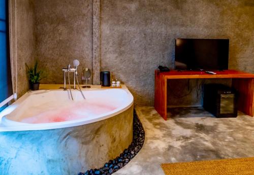 una grande vasca da bagno in una camera con TV di R resident resort a Phetchaburi