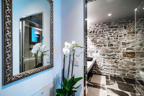 a bathroom with a mirror and a stone wall at Suite Lo Storico - The House Of Travelers in Como