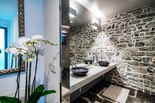 a bathroom with two sinks and a stone wall at Suite Lo Storico - The House Of Travelers in Como