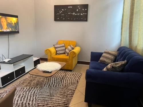 a living room with a blue couch and a yellow chair at Romantic, Stunning & Authentic Ensuited Master Bedroom in Dar es Salaam