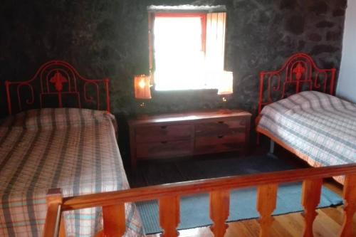 a bedroom with two twin beds and a window at Casas da Figueira in São Roque do Pico