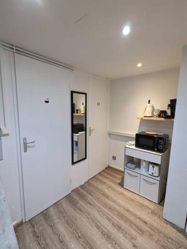 a room with a kitchen with a door and a microwave at RDC Studio Agen Hyper Centre - Clim - Voltaire in Agen
