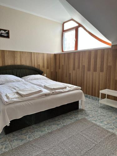 1 dormitorio con 1 cama grande y ventana en Muskátli Panzió és Étterem, en Újhartyán