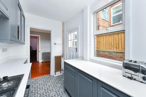 a kitchen with white counters and a window at Highfield Grove - Beautifully Bright 2BR, West Bridgford in Nottingham