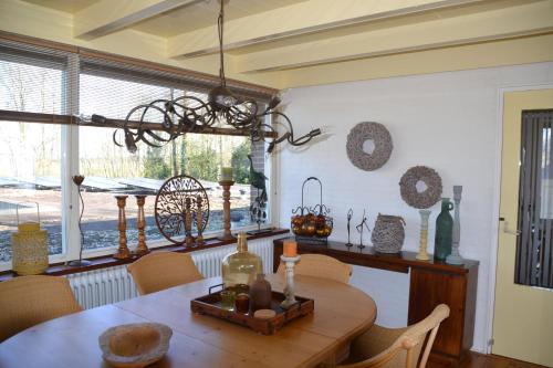 a dining room with a wooden table and a chandelier at Vakantie Accommodatie Egelantier in Dwingeloo