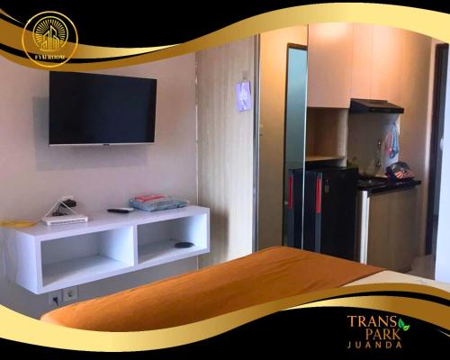 a room with a tv and a kitchen with a refrigerator at Apartemen Transpark Juanda Bekasi by FYM ROOM in Padurenan