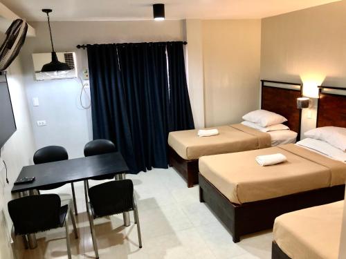 a hotel room with two beds and a desk at Delle Suites in General Santos
